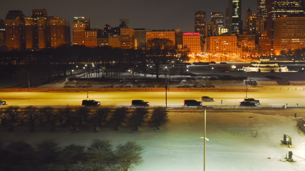 City skyline at night with illuminated buildings and foggy foreground.