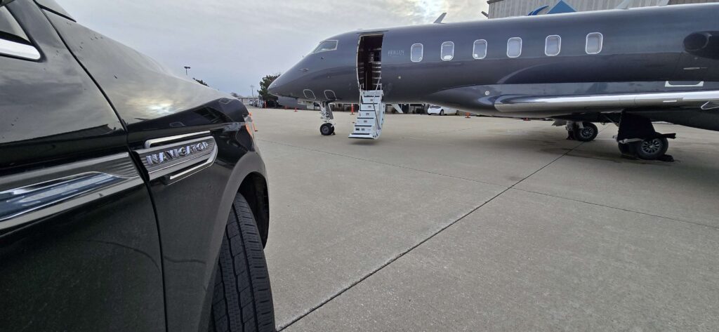 Private jet parked on tarmac with vehicle nearby.